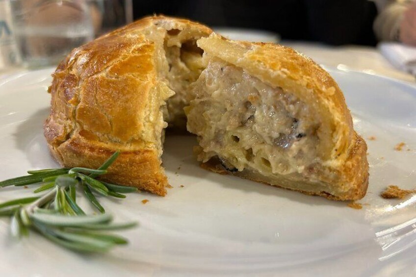 A pastry with a golden-brown crust, cut in half, revealing a creamy filling. 1