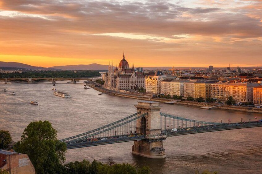 A river with a bridge, a historic building, and a cityscape at sunset. 4