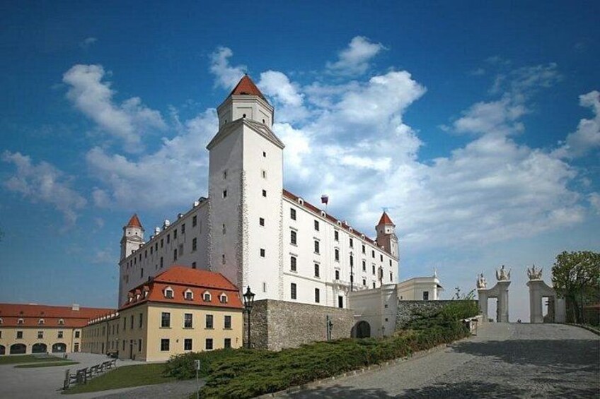 A historic castle with a central tower, a red-roofed building, and a paved courtyard. 2