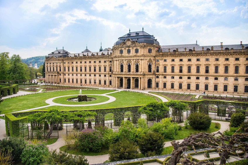 A large historic building with a symmetrical facade, a central circular garden, and a formal park layout. 5