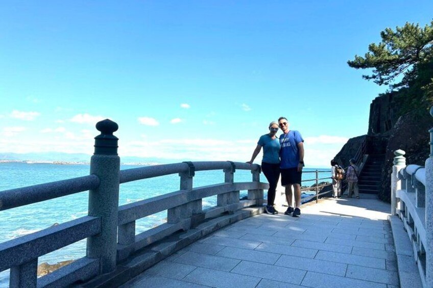 A coastal walkway with a railing, a clear sky, and a distant shoreline. 3