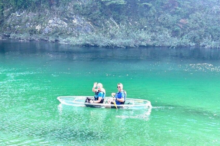 Two people in a small boat on a clear turquoise lake surrounded by rocky cliffs. 5