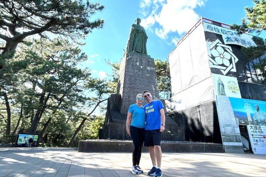 Two people standing in front of a statue with a large sign in the background. 4