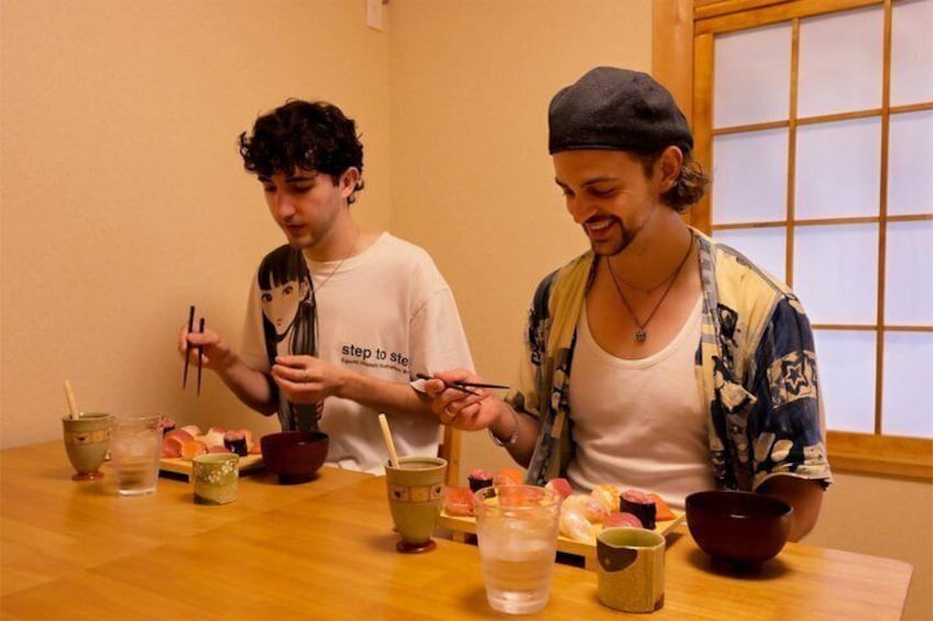 Two people sitting at a wooden table with bowls of food and drinks. 2