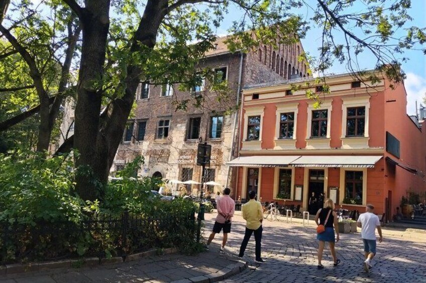 A cobblestone street with pedestrians, a tree-lined sidewalk, and historic buildings. 4