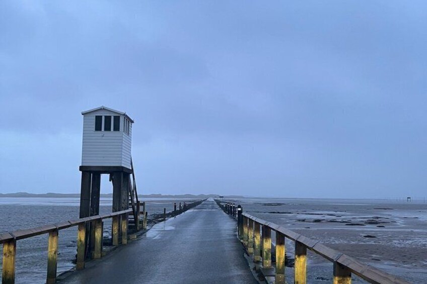 A wooden pier extending into a body of water with a lifeguard tower at the end. 3