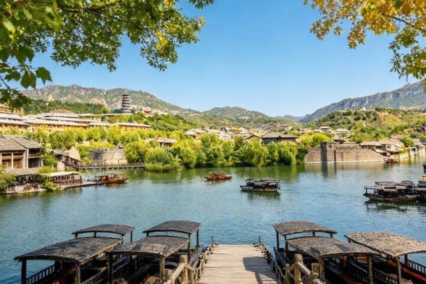 A riverside scene with traditional boats, wooden walkways, and historic buildings. 1