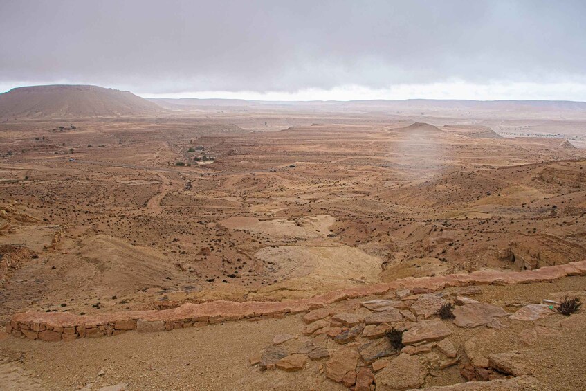 A vast desert landscape with rocky terrain and distant hills. 5