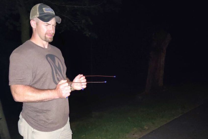 A person holding a stringed object outdoors at night. 2