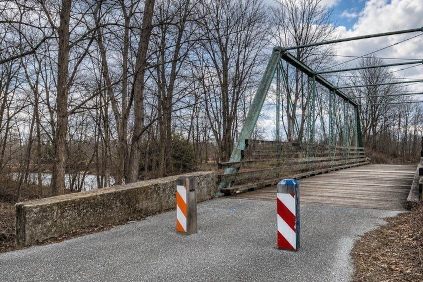 A bridge with metal railings, a gravel path, and trees in the background. 3