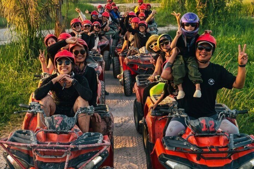 A group of people on ATVs, wearing helmets, on a dirt path surrounded by greenery. 1