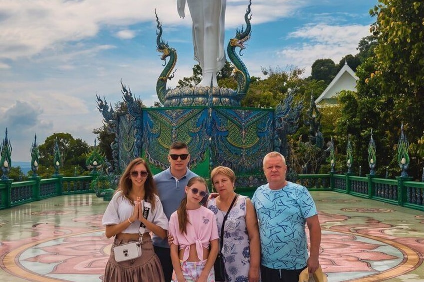 A group of people posing in front of a colorful, ornate fountain with a dragon statue. 3