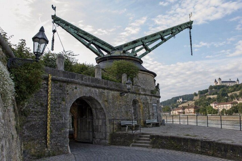 A historic stone bridge with a mechanical lift, a stone archway, and a river with a distant castle. 2