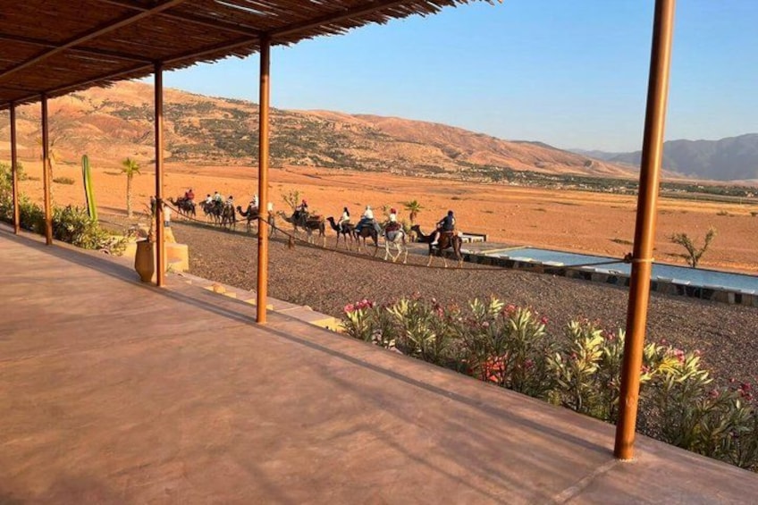 A desert landscape with a group of people riding camels. 5