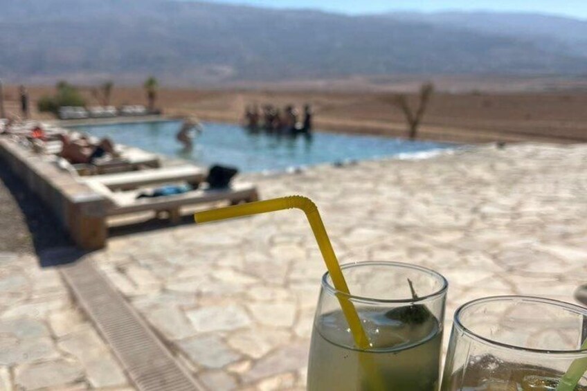 A poolside with a drink, a lounge area, and a mountainous landscape in the background. 4