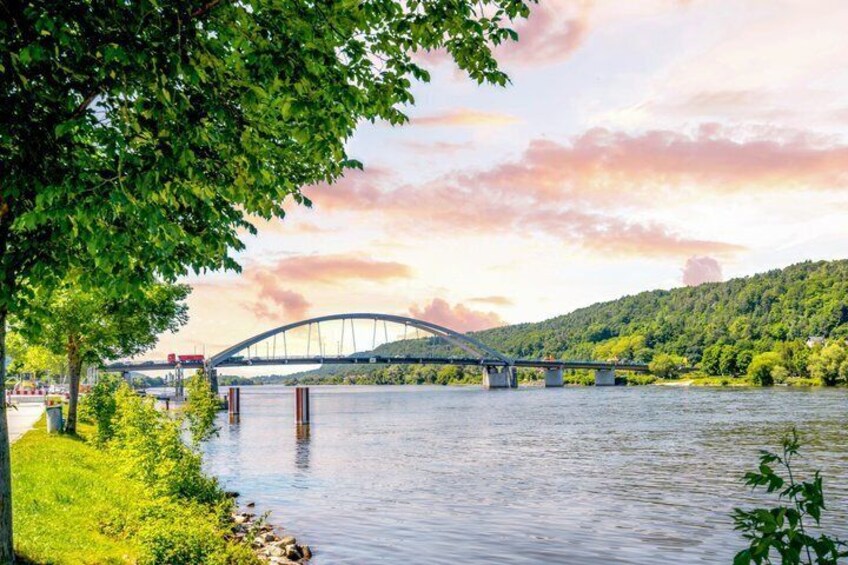 A river with a bridge, greenery, and a hilly landscape. 5