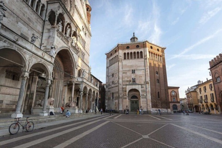 A historic square with a prominent building featuring arches and columns, a tiled pavement, and a clear sky. 4