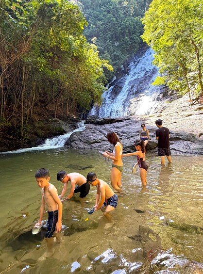 A waterfall, clear water, and people in bathing suits. 1