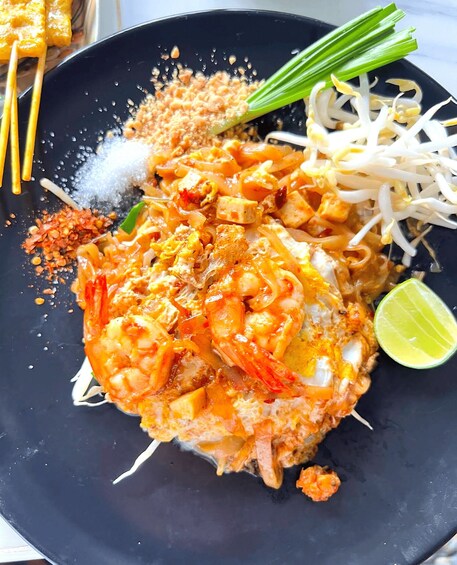 A plate of Pad Thai with shrimp, bean sprouts, lime, and a lime wedge. 4