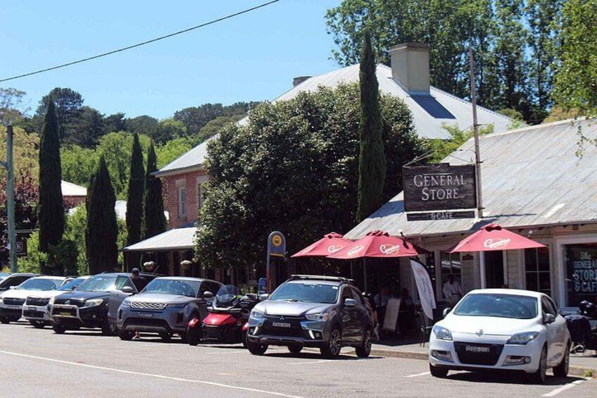 A street with parked cars, a General Store, and red umbrellas. 4
