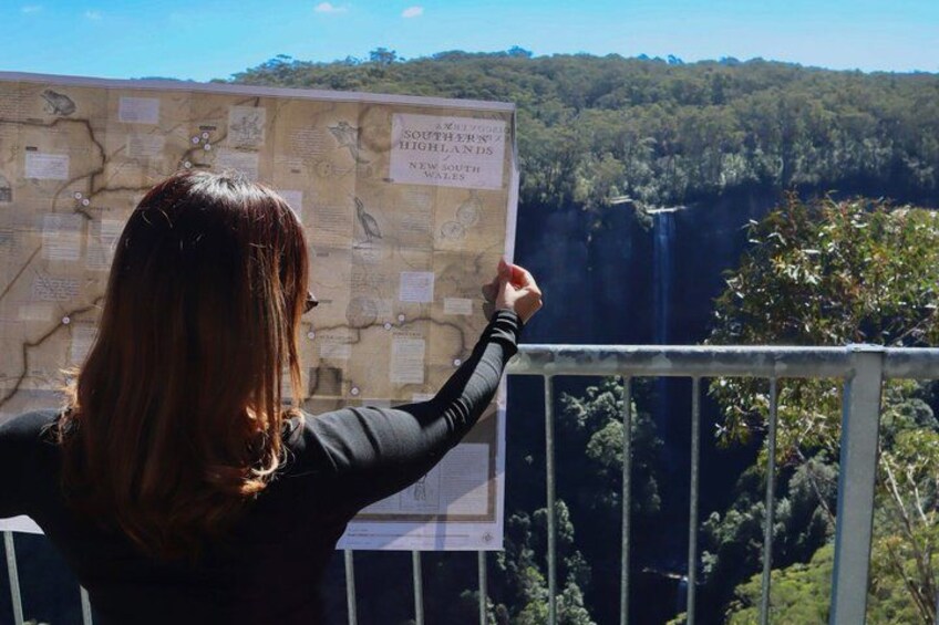 A person pointing at a map with a waterfall in the background. 1