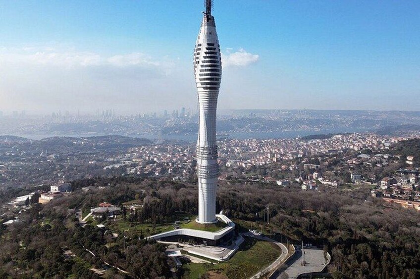 A tall, slender tower with a unique design, surrounded by a cityscape and greenery. 3
