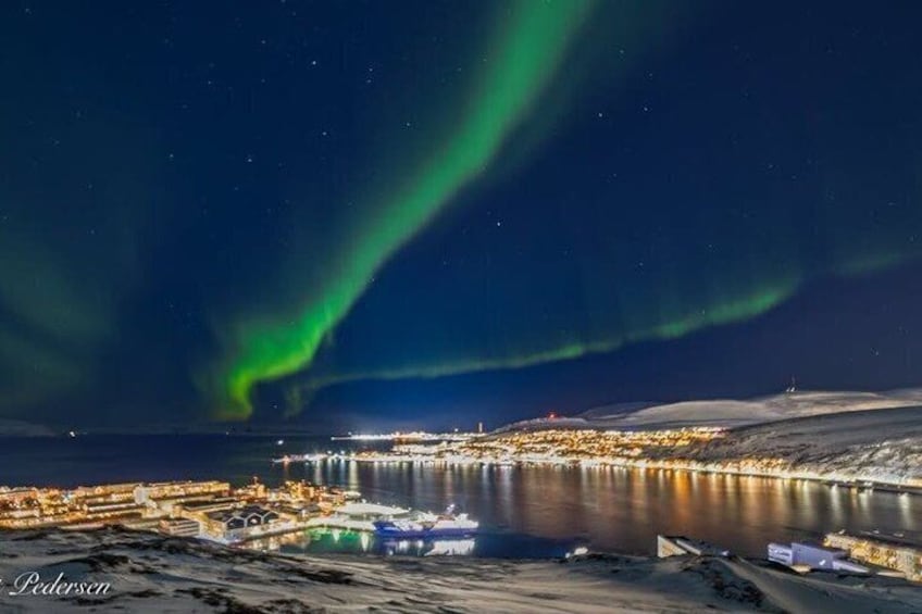 A coastal town with a view of the northern lights over the ocean. 2