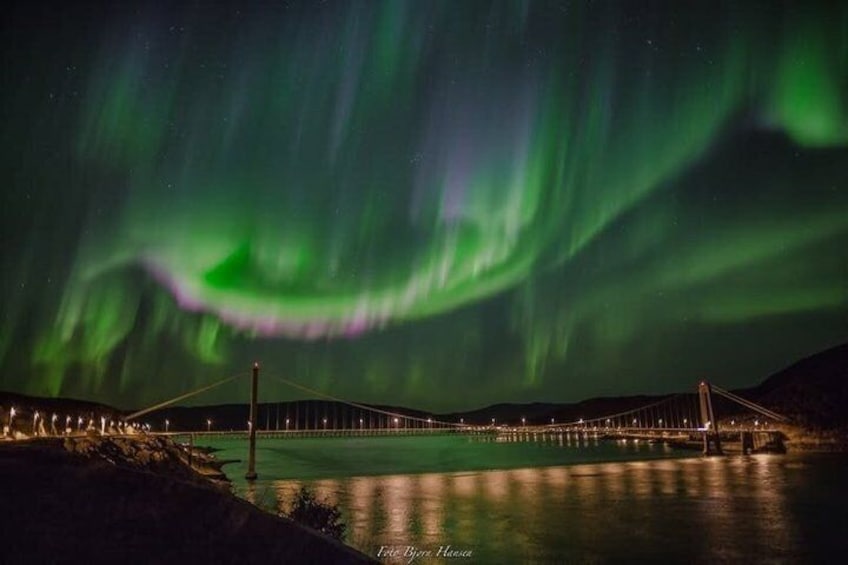 A bridge over water with the Northern Lights in the background. 1
