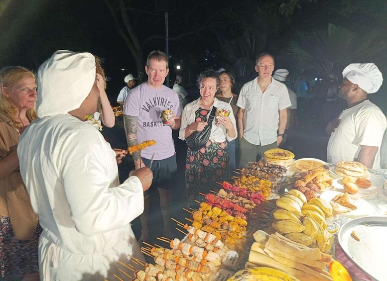 A food stall with skewers and flatbreads, attended by a vendor and customers. 2