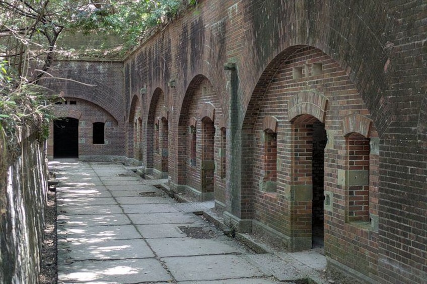 A brick building with arched doorways and a concrete pathway. 1