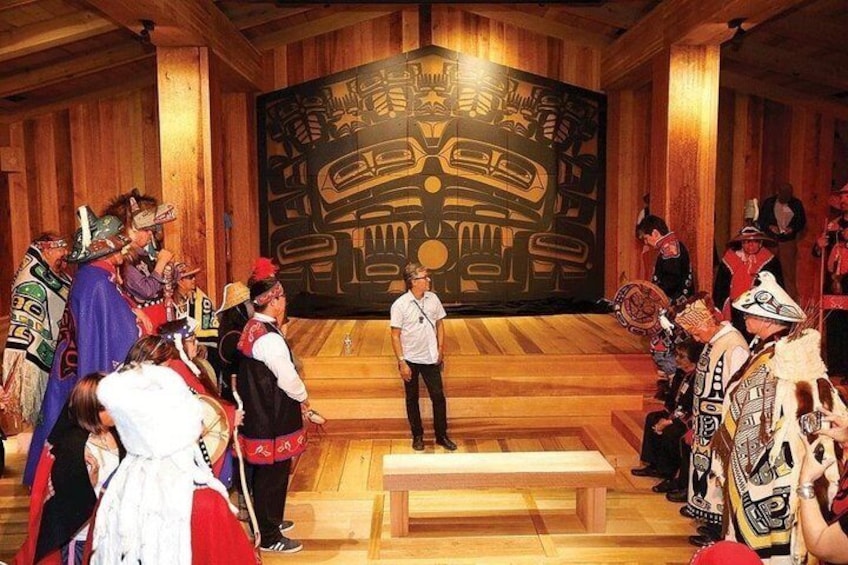 A person standing on a wooden platform in front of a large totem. 3
