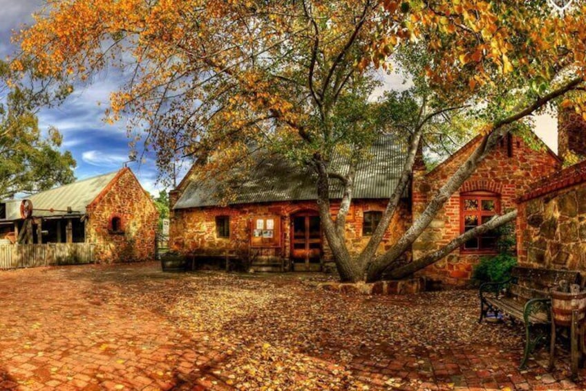 A rustic stone building with a tree in front, surrounded by a cobblestone courtyard. 5