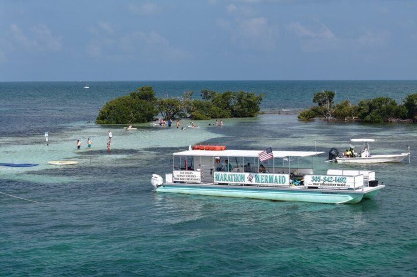 A boat named 'Marathon Mermaid' with a clear view of the ocean and a small island with trees in the background. 3