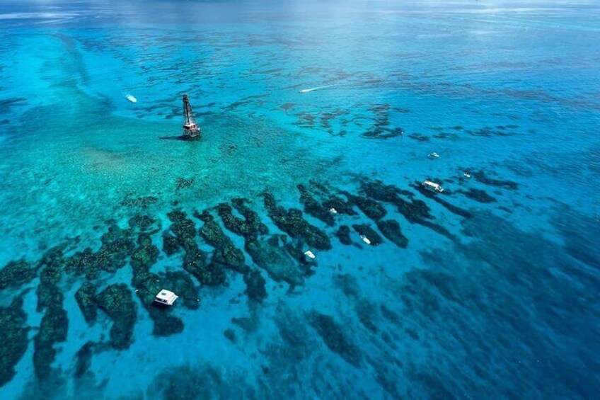 An aerial view of a clear blue sea with a submerged structure and several boats. 1