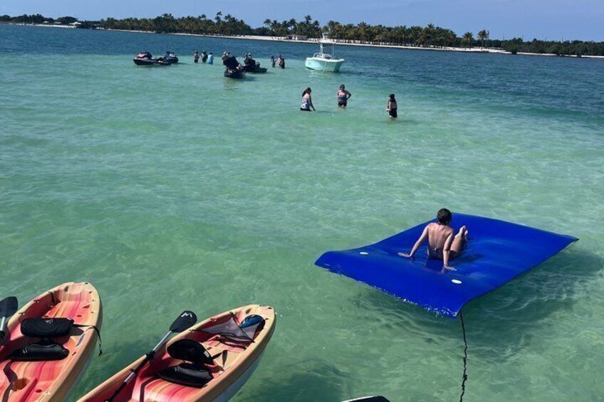 A beach with people in the water, boats, and a blue mat. 4