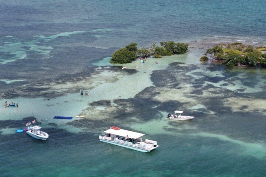 A tropical island with clear turquoise waters, boats, and people. 2