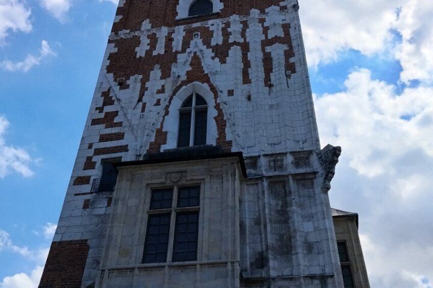 A tall, weathered tower with a patterned facade, a large arched window, and a smaller window below. 5