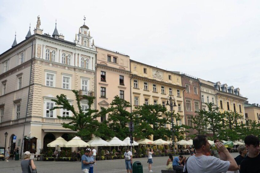 A historic building with classical architecture, a public square with people, and outdoor seating areas. 3