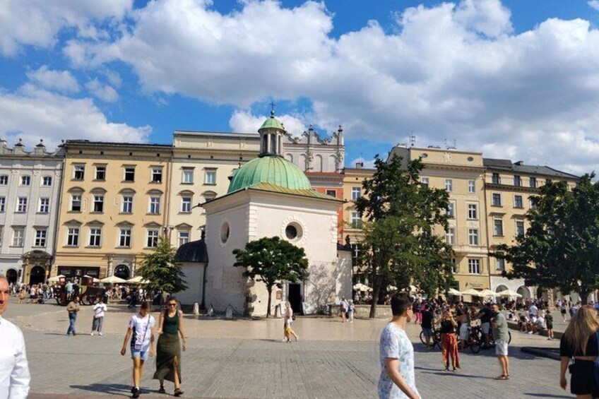 A public square with a prominent green-domed building, surrounded by historic buildings. 1