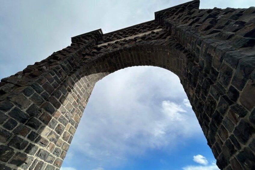 Un puente de piedra con arco contra un cielo despejado. 4
