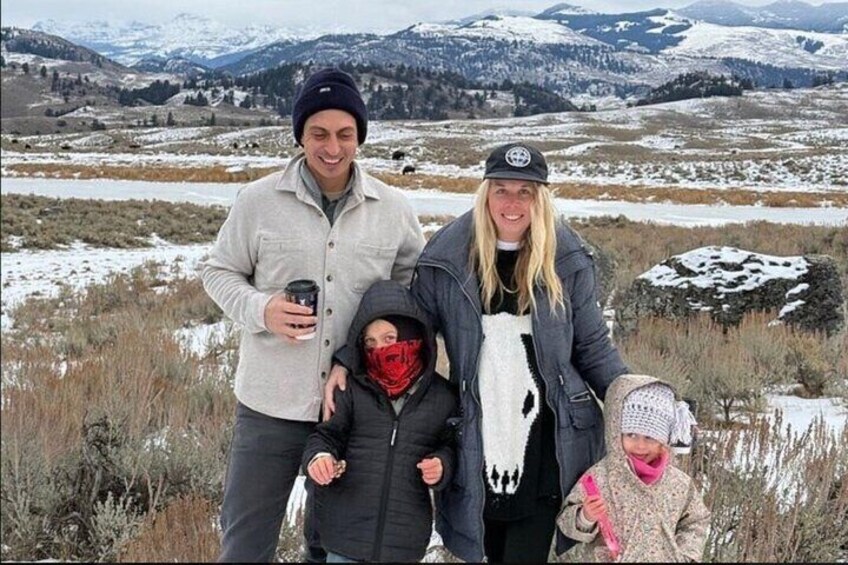 Una familia de cuatro personas en un paisaje nevado con montañas al fondo. 2
