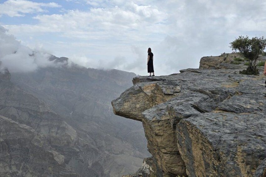 A person standing on a rocky cliff overlooking a mountainous landscape. 2