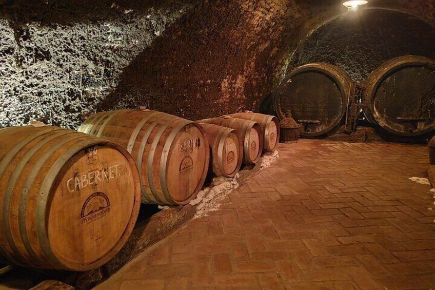 Wooden barrels in a cellar with stone walls and a brick floor. 2