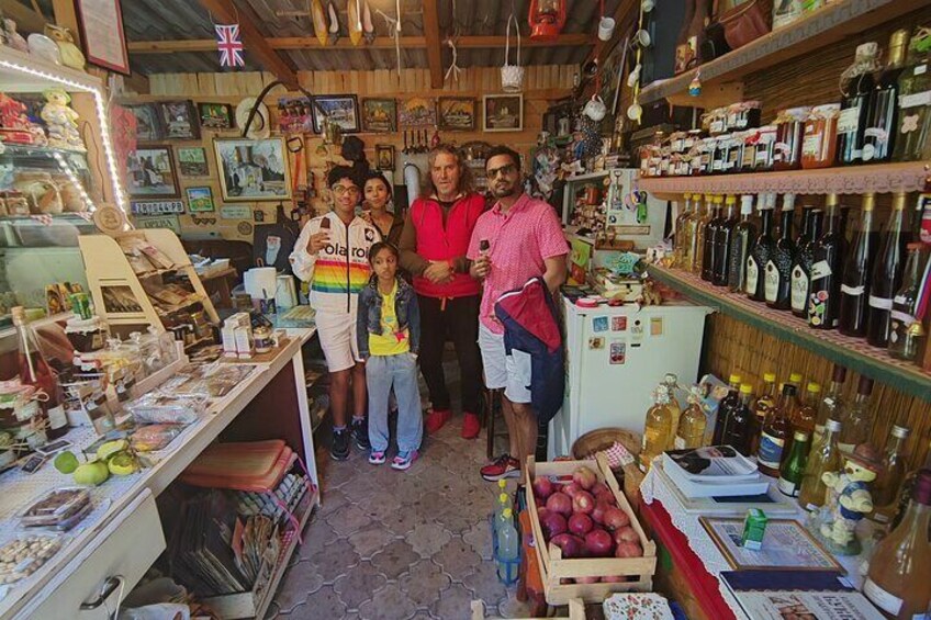 A family in a cluttered shop with shelves of bottles and various items. 4