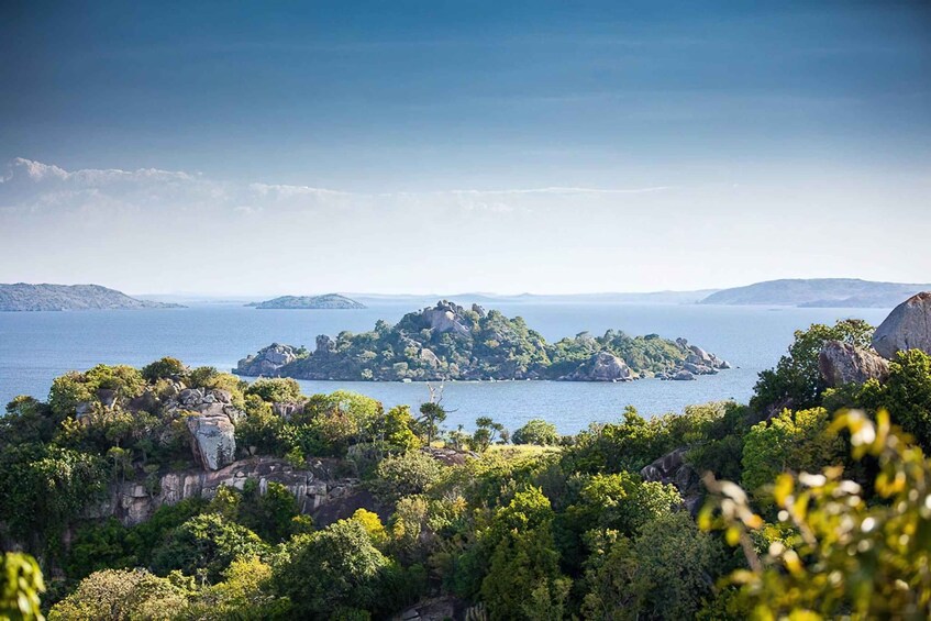 A coastal landscape with a prominent rocky island surrounded by lush greenery and a calm sea. 3