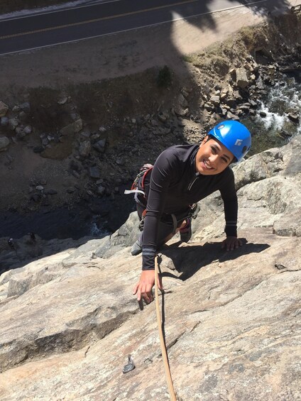 A person climbing a rocky slope with a rope. 4