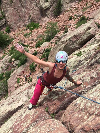 A person rappelling down a rocky cliff with a helmet and harness. 2