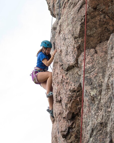 A person climbing a rocky cliff with a rope. 5