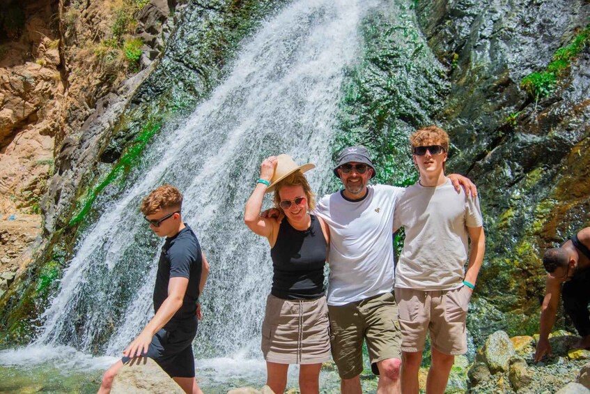 A group of people standing in front of a waterfall. 1