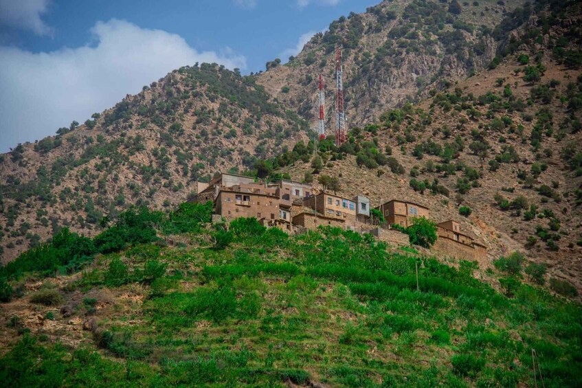 A hillside settlement with traditional buildings, a prominent communication tower, and a rugged mountainous backdrop. 3